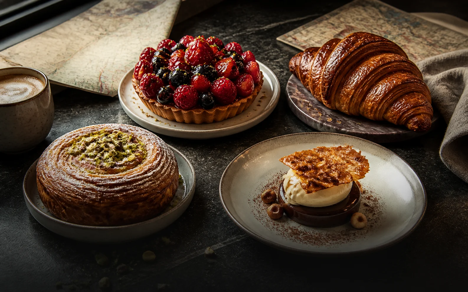 A curated spread of pastries including a berry tart, croissant, pistachio pastry, and plated dessert